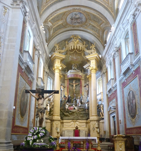       Ornate interior of a church with religious statues and columns.
  