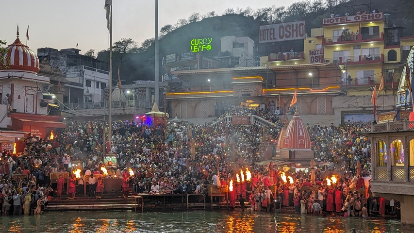 Gathering of people near a river with a lit background.