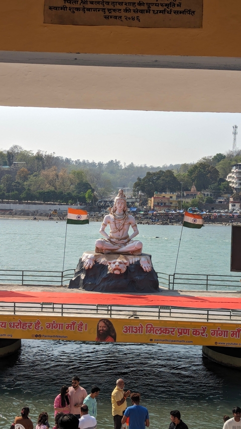 Statue of a deity near a river with flags.