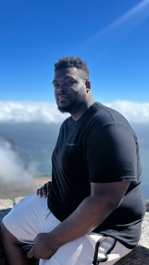       Close-up of a person with a sky and ocean in the background.
  