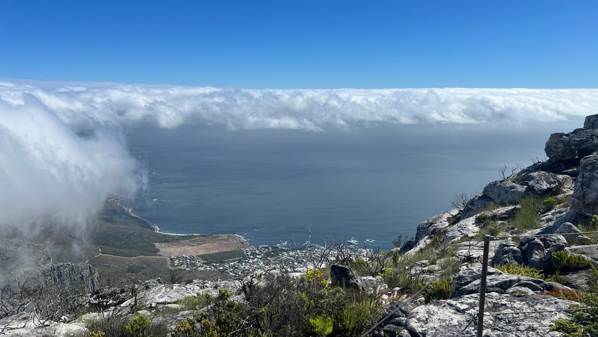       View from a mountain top overlooking clouds and the ocean.
  