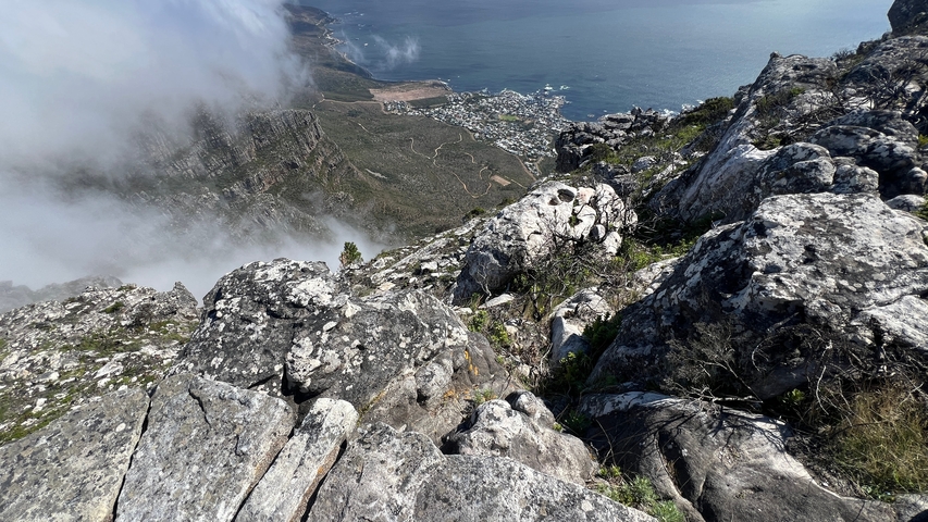       View from mountain cliffs with clouds over the ocean below.
  