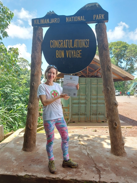       Woman holding a certificate in front of a building.
  
