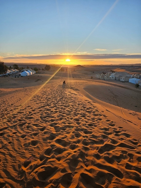       Desert landscape with a person silhouetted at sunset.
  