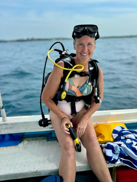 A person on a boat preparing for scuba diving with ocean in the background.