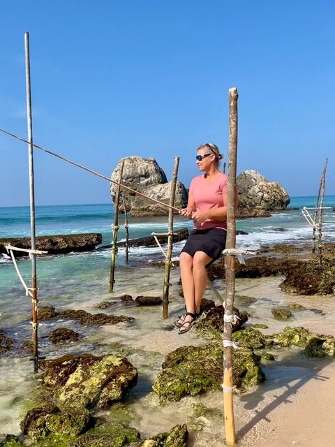 Woman practicing traditional stilt fishing in the ocean.