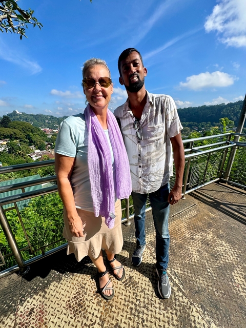 Two people standing on a viewing platform overlooking a lush landscape.