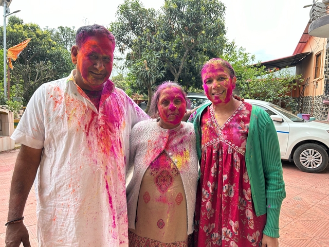 Group of three people with colorful Holi powders on them.