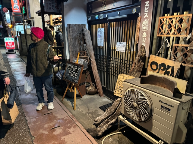 People in a street market with a signboard for curry rice.