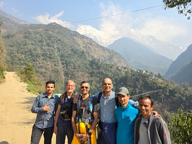 People posing with mountains in the background on a hiking trail.