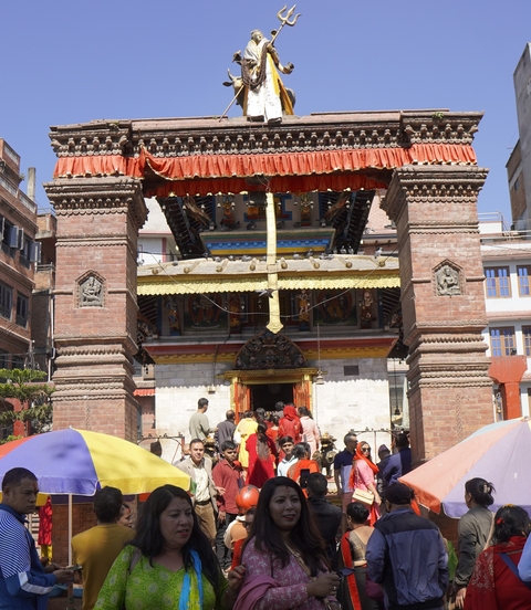       People in front of a temple entrance with ornate carvings.
  