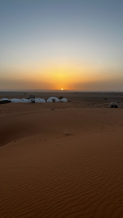 Desert tents with sunset in the background.