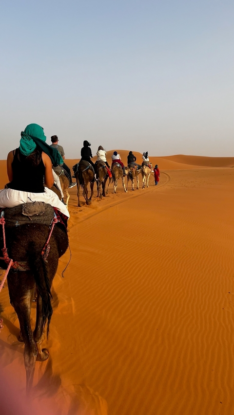 People riding camels on sand dunes.