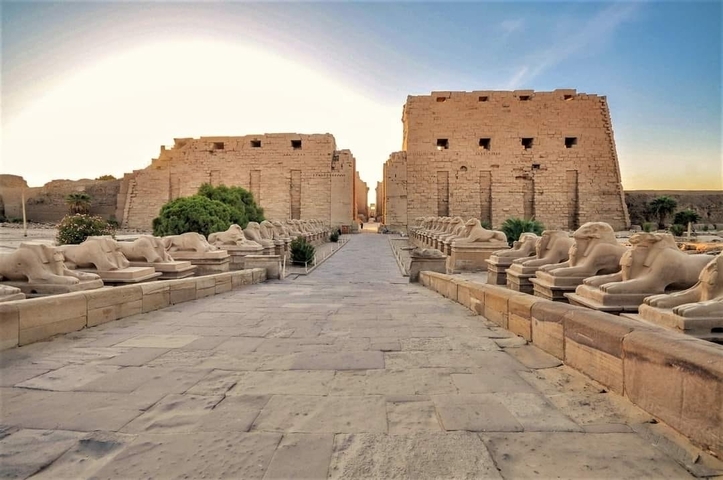 Avenue of Sphinxes leading to Karnak Temple, bathed in golden sunset light.
