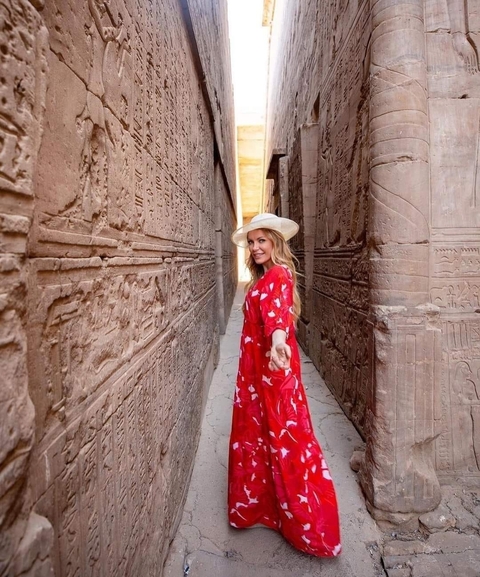 Woman in a red dress in ancient Egyptian corridor.