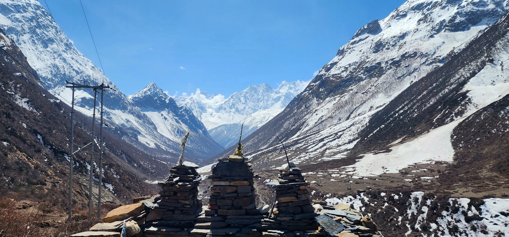 Snow-capped mountains and stone structures under a clear blue sky.