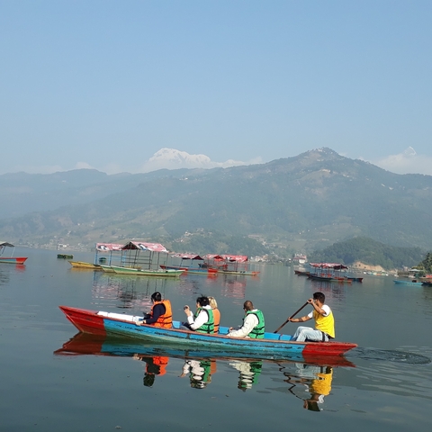 Tourists boating on a lake surrounded by hills.