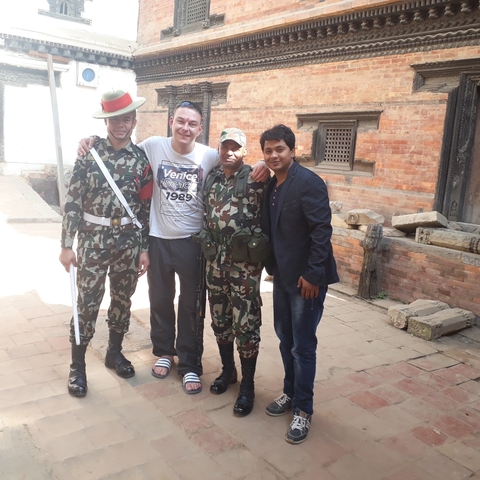 Four men, two in uniform posing for a photo.