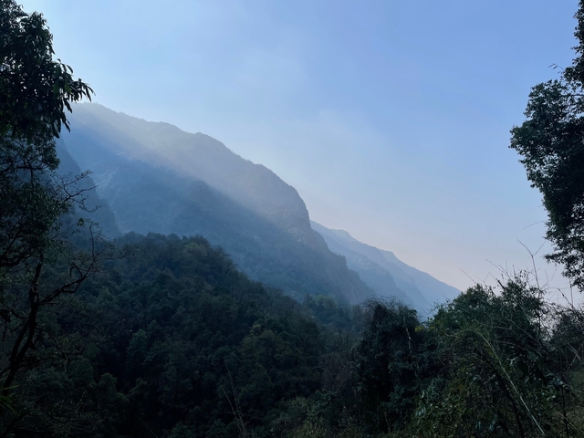 Misty mountain landscape with layers of hills and gentle sunlight.