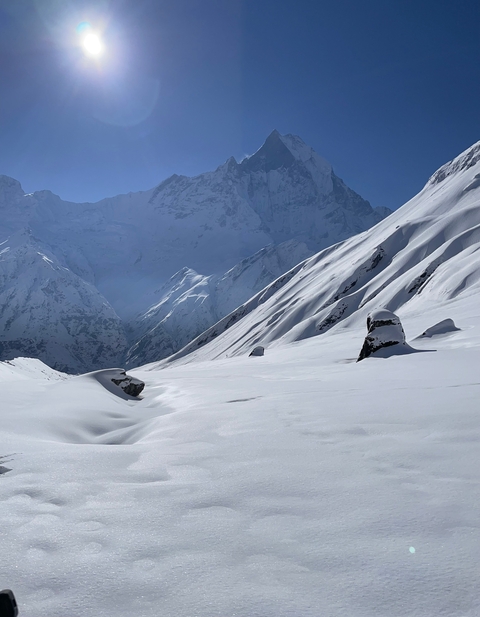 Snow-covered mountains with rugged terrain under a clear blue sky.