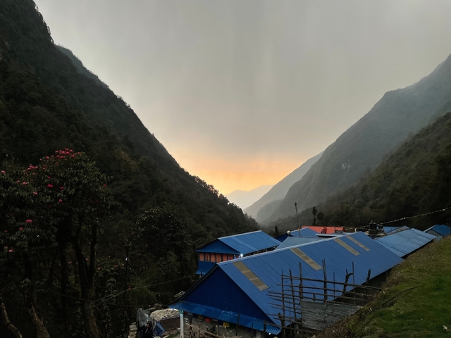 Valley with a view of sunset over distant mountains and blue-roofed buildings.