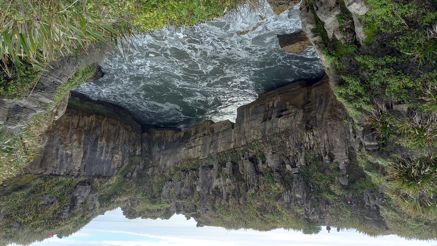 Coastal rock formation with water rushing through.