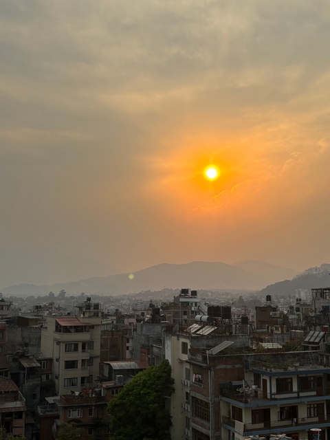 A city skyline with a sunset sky and mountain silhouette.