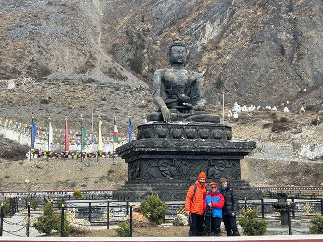 Tourists posing in front of a large Buddha statue.