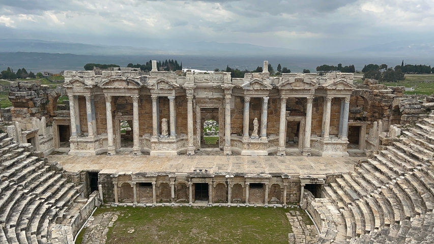 Ancient amphitheater ruins with dramatic sky.