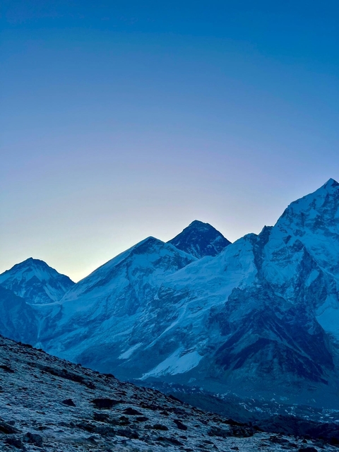 Snow-capped mountains at dawn with a clear sky.