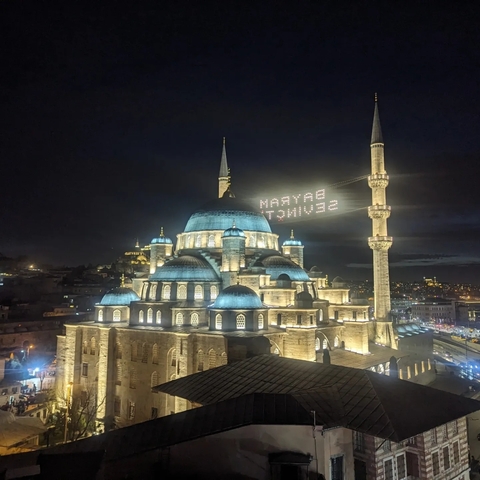       Illuminated mosque with minarets at night.
  