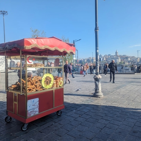       Street vendor selling simit near a waterfront promenade.
  