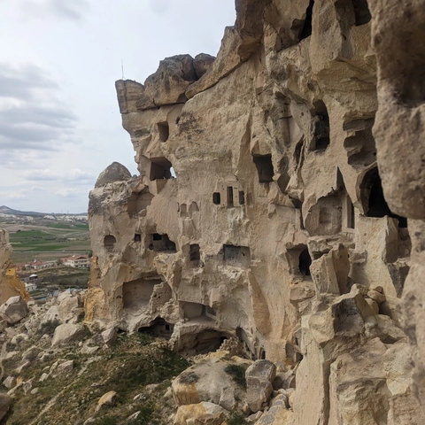       Rock formations with cave dwellings in a semi-arid landscape.
  