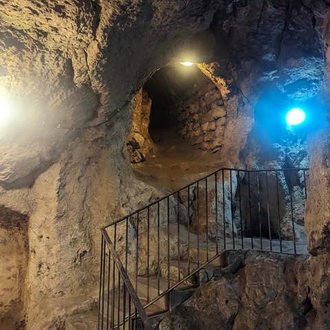       Underground cave scene with lit passageways and wooden stairs.
  