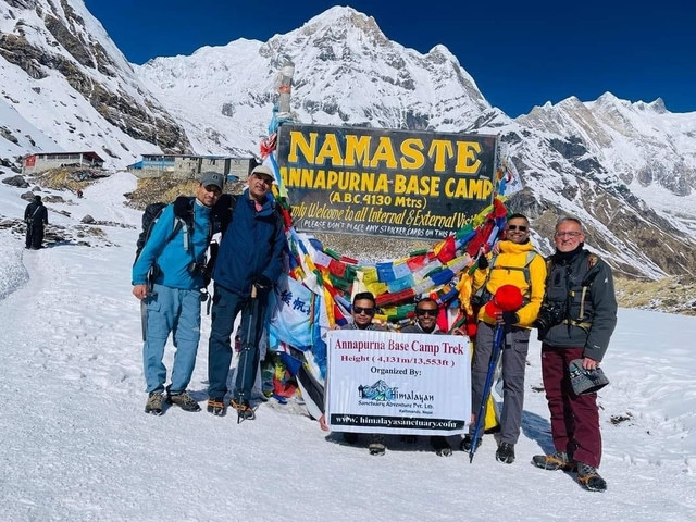 Group of trekkers at Annapurna Base Camp with a sign.