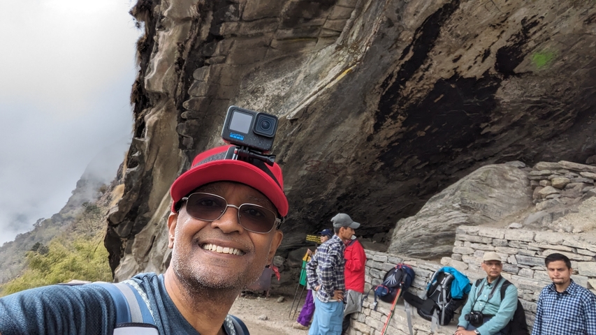 Man taking a selfie on a mountain trail with others behind.