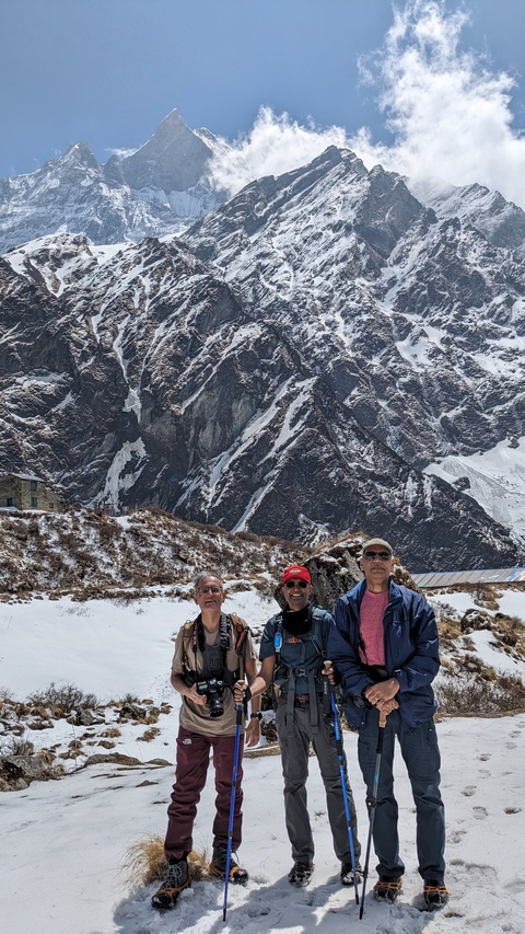 Group of people posing with a snowy mountain backdrop.
