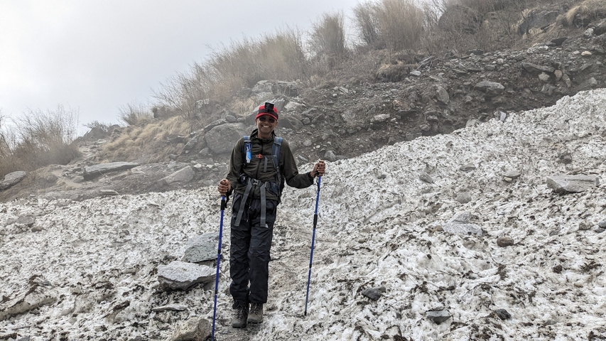Man standing in the snow holding trekking poles.