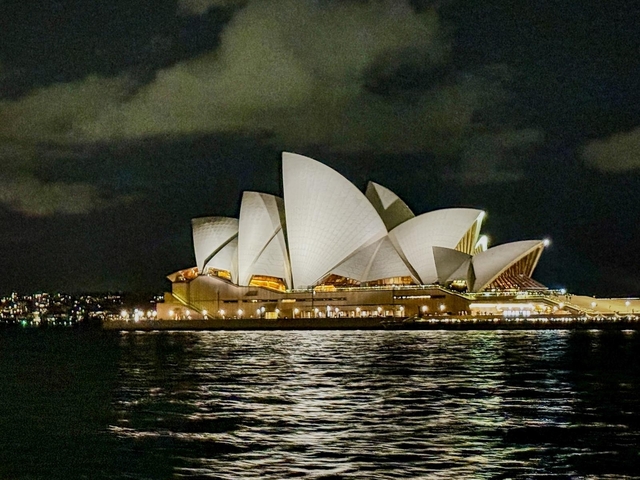       Illuminated architectural landmark by the water at night.
  