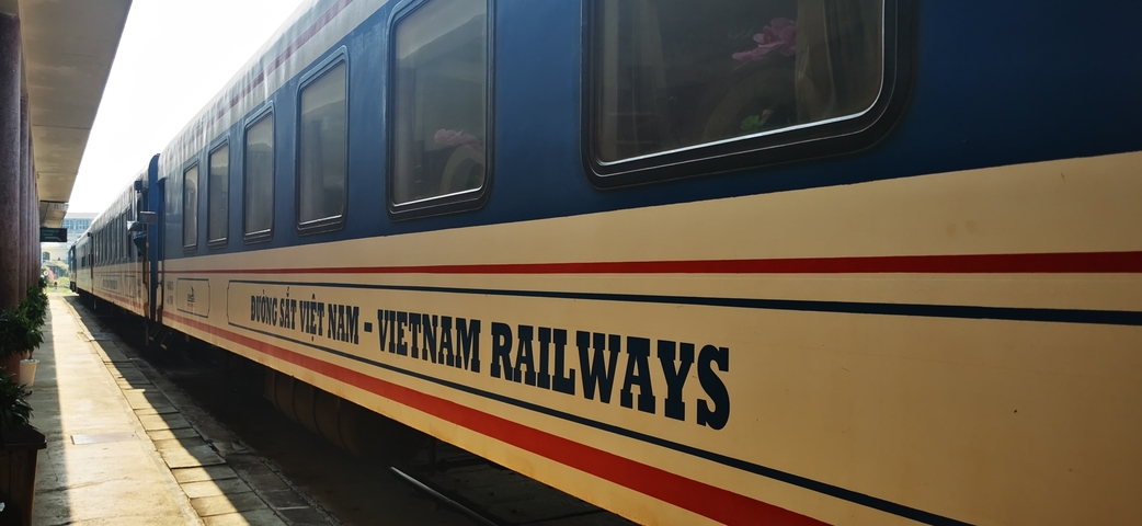       Vietnam Railways train parked at a station.
  