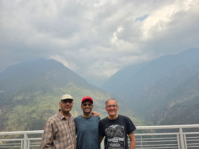 Three people posing with misty mountains in the background.