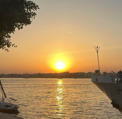 A beautiful sunset over a calm river with a boat in the foreground.