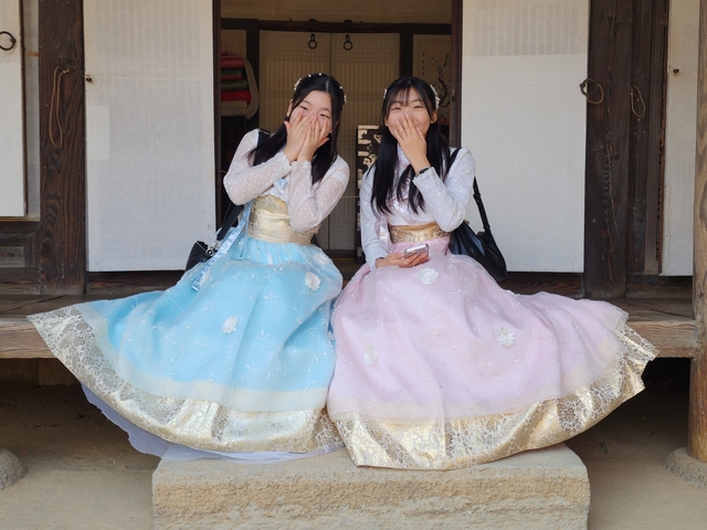       Two women in traditional Korean hanbok sitting and smiling.
  