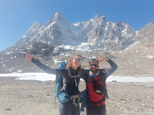       Two hikers posing in front of snowy mountains.
  