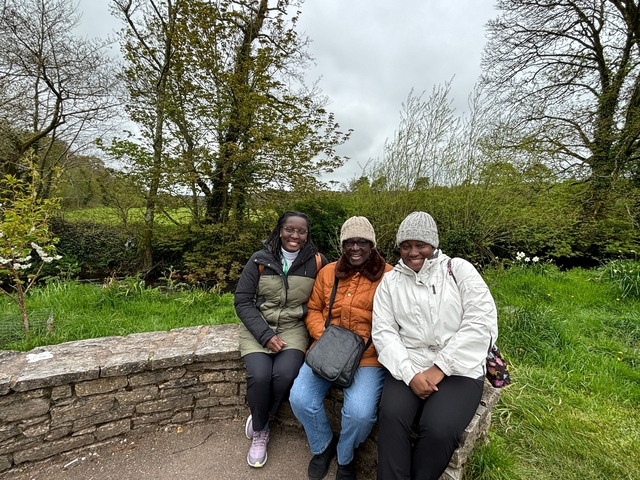       Three people sitting on a stone wall outdoors.
  