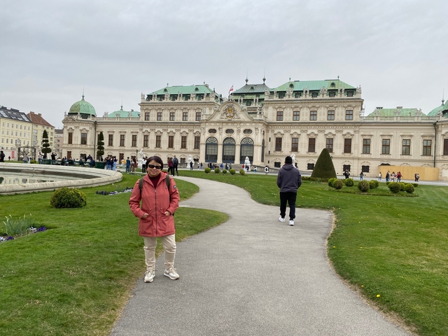 A person standing in front of a large, historic building with a green roof.