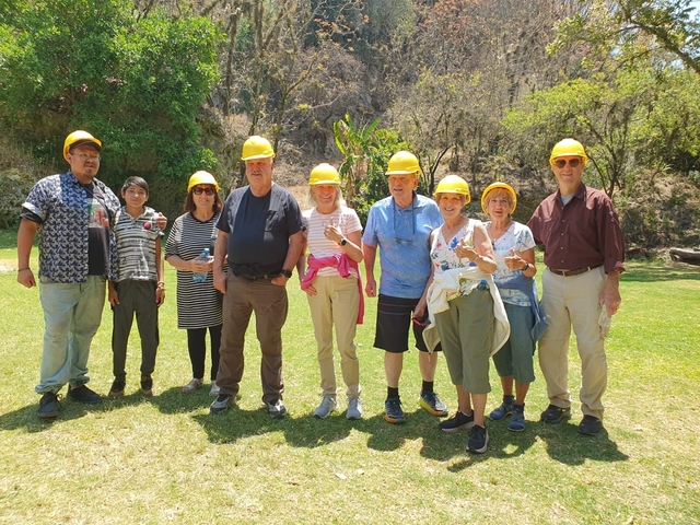       Group of people wearing helmets standing outdoors on a grassy area.
  