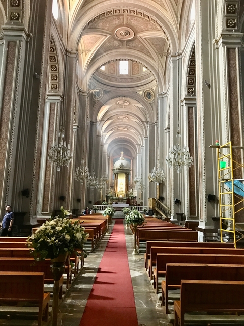       Interior of a large ornate church with chandeliers.
  