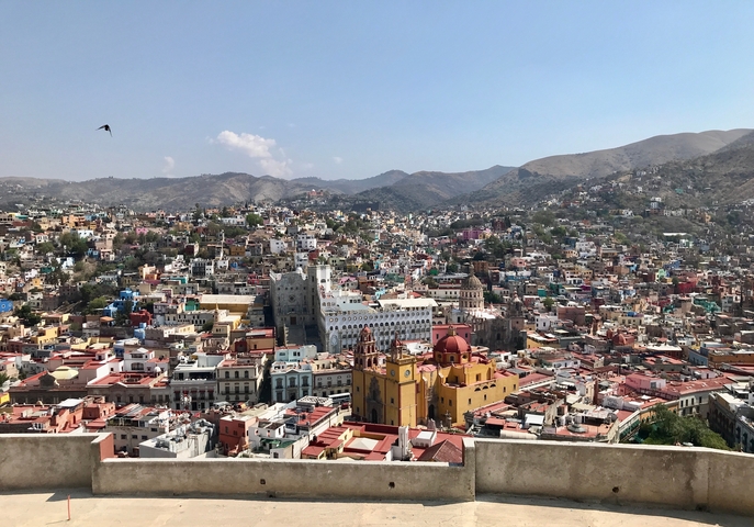       Panoramic view of a colorful city with hills in the background.
  