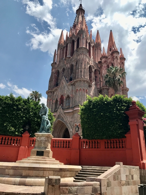      Gothic-style church surrounded by trees, with a statue in front.
  